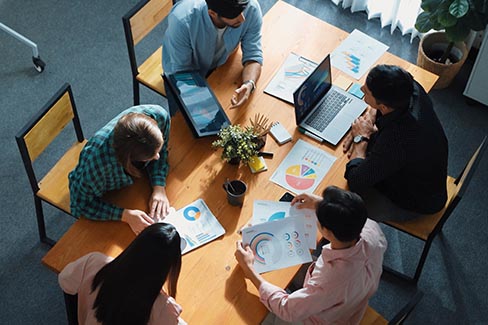 background image above team huddled around a meeting desk